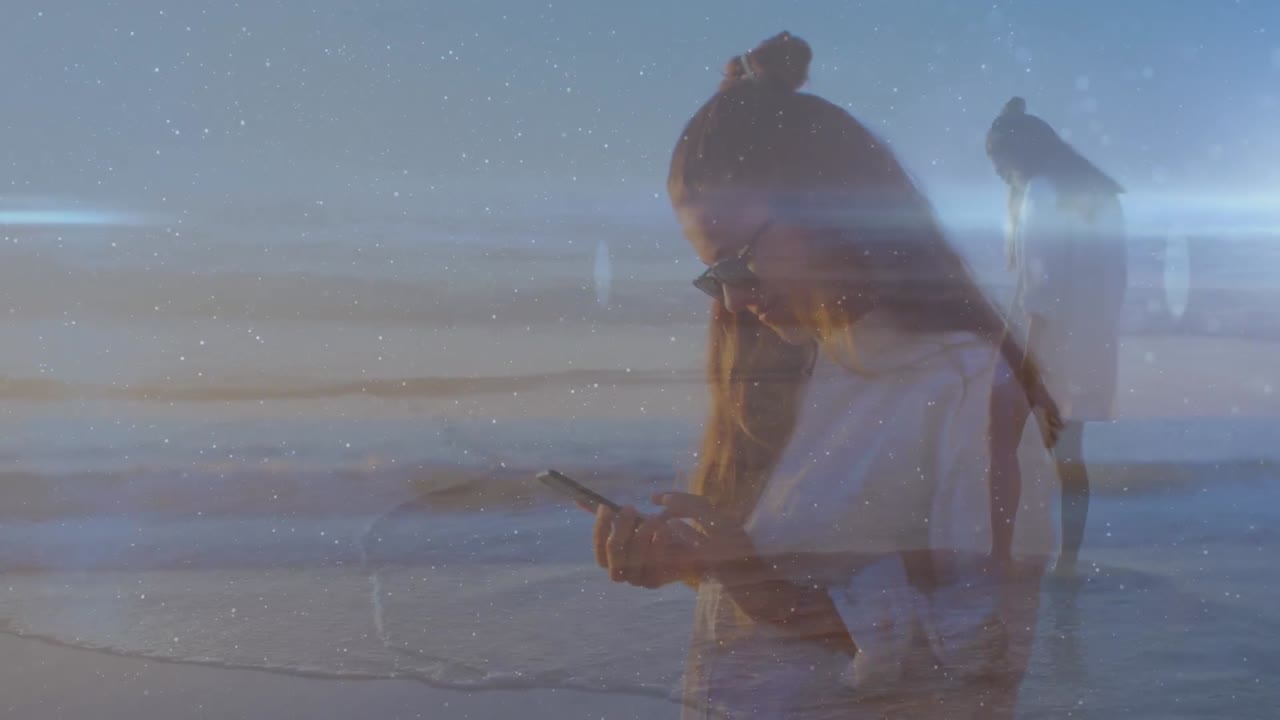 해변에서 스마트 폰을 사용하는 두 인종의 여성 위에 빛의 트레일의 애니메이션