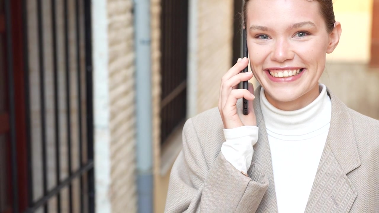 Una donna impegnata in una conversazione telefonica in un affollato vicolo urbano, in mezzo alla vita cittadina.