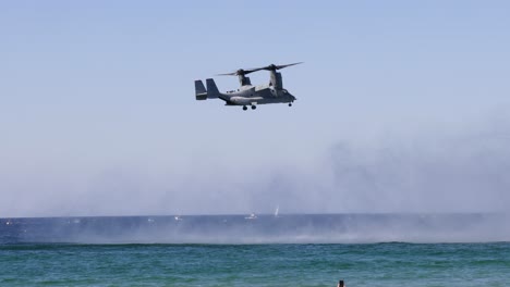 helicopter hovers over sea, creating water spray