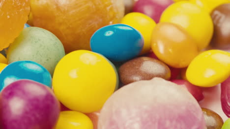 colorful dragee candies, lollipops, bonbons on white background, move in circle, side view close-up. summer bright texture studio shot for store, supermarket. mix of children's sweets made of sugar.
