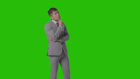 three quarter length shot of serious businessman in suit thinking against green screen 1