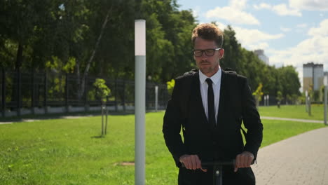 businessman riding an electric scooter in a park