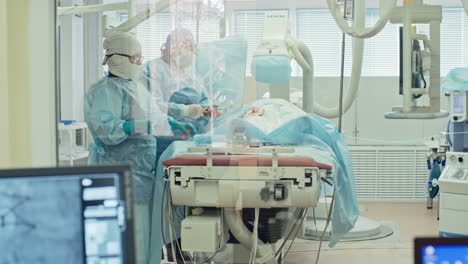 outside view of an operating room, two surgeons operate on a patient lying on hospital bed