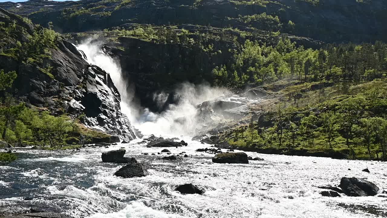 Nykkjesoyn vesiputous syöksyy alas Hardangerviddalta, luoden usvaa ja pisaroita, jotka nousevat auringonvaloon Husedalenissa, Norjassa.