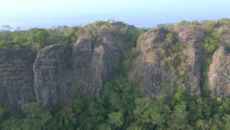 Aerial-drone-shot-from-rocky-mountain-side-of-Nglanggeran-prehistoric-volcano,-Yogyakarta,-Indonesia---4K-drone-shot