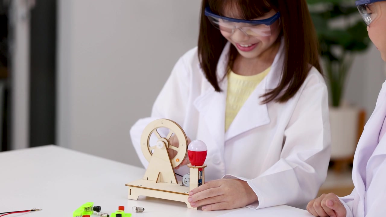 Young student in lab coat examines wooden light model during classroom STEM science experiment.