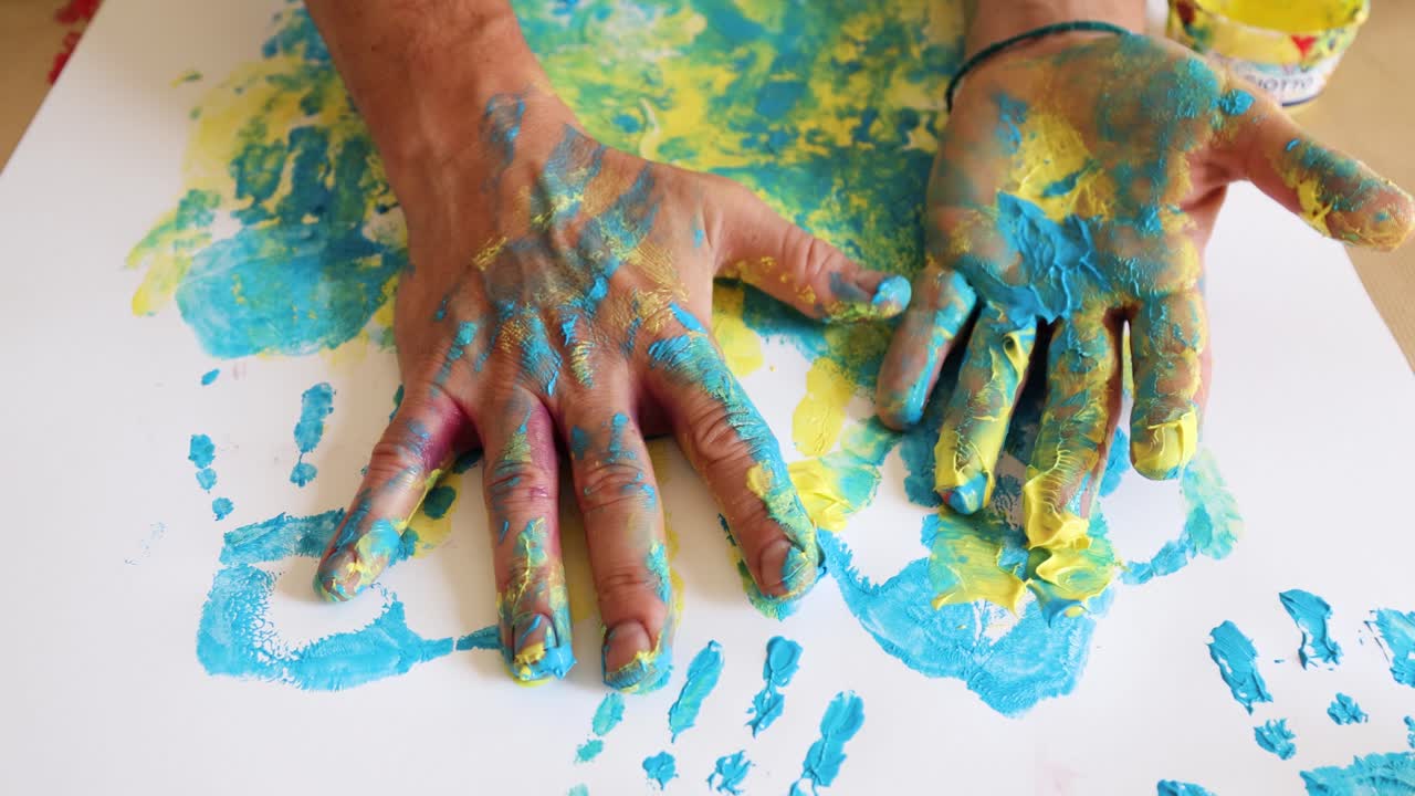 manos de un hombre adulto cubiertas con pintura azul y amarilla para huellas artísticas para la solidaridad con ucrania