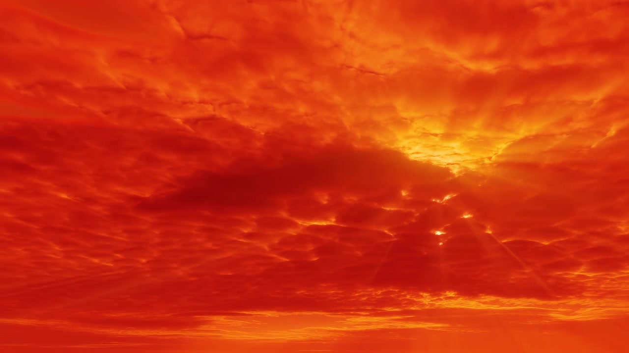 Cielo de atardecer rojo anaranjado ardiente con nubes dramáticas en capas y rayos dorados perforando el horizonte, fundido cinematográfico