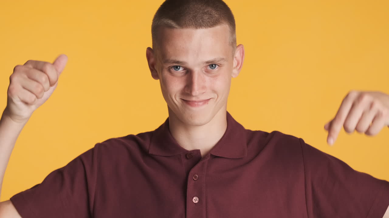 un joven sonriente señalando hacia abajo.