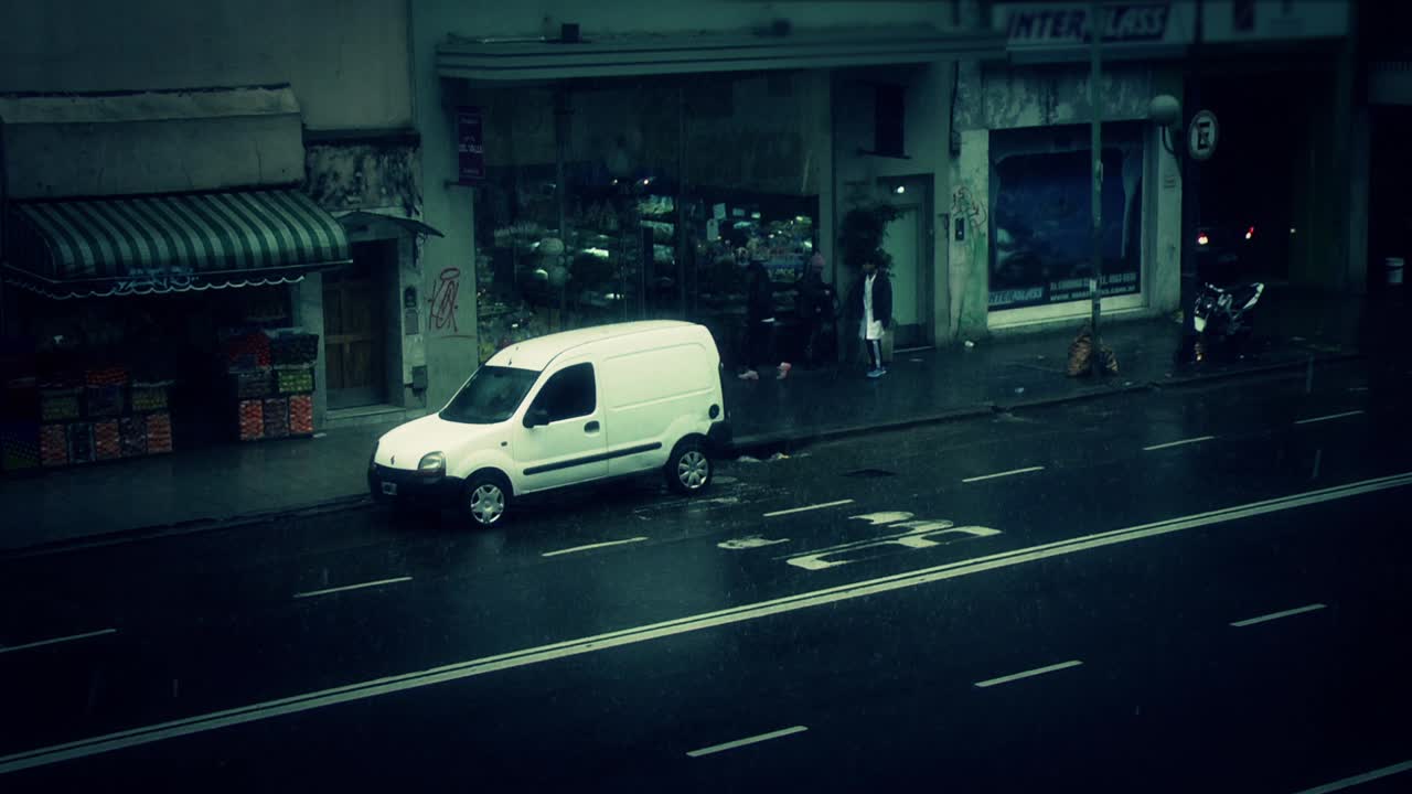 Giornata piovosa su una strada urbana con auto e pedoni