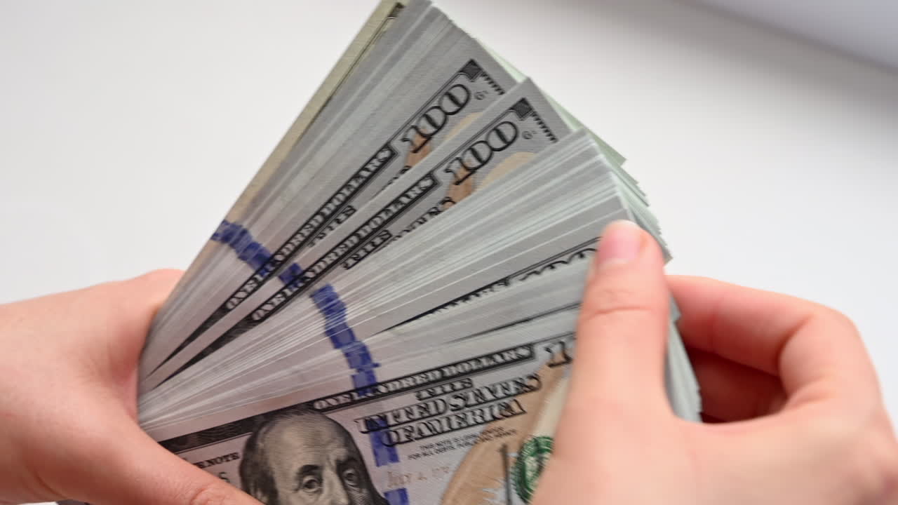 Close up of female hands holding a wide fan of one hundred dollar bills