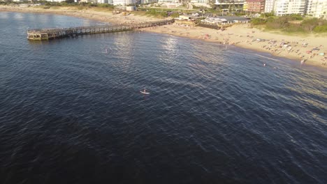 Couple-on-sup-board-paddling-over-sea-waters-along-Punta-del-Este-beach,-Uruguay