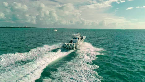 Velocidad-De-Crucero-Del-Barco-De-La-Consola-Central-Del-Motor-Cuádruple-Aéreo-Con-Velero-En-El-Fondo-En-Las-Aguas-Costeras-Azules