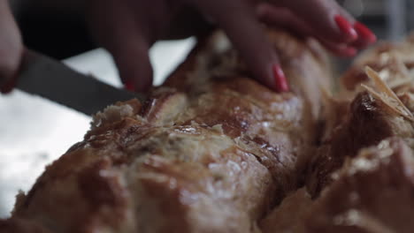 Woman-cutting-big-sausage-roll,-red-nails