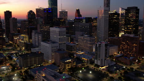 Aerial-hyperlapse-backwards-over-streets-in-downtown-Houston,-sunset-in-Tx,-USA