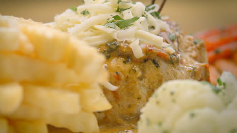 mustard chicken with french fries, salad, and grated cheese, close-up, mediterranean