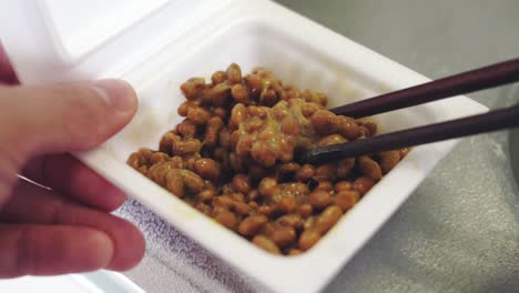 eating a sticky natto using a wooden chopsticks - traditional japanese food. - close up shot