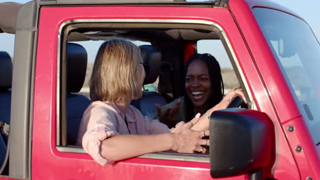 young african american woman and young caucasian woman share a laugh in a car on a road trip, with c