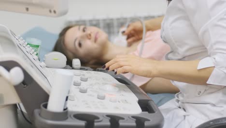 ultrasound scanning diagnostic of young woman thyroid gland in clinic. woman doctor runs ultrasound sensor over patient's neck.