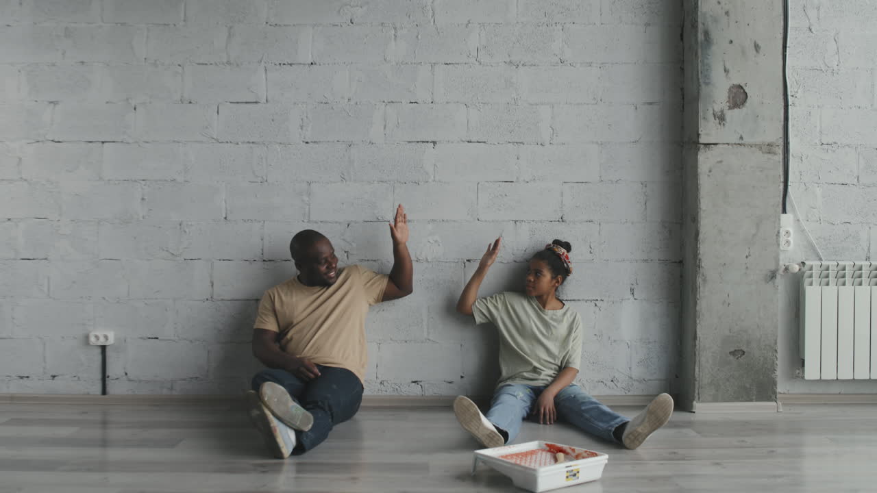 Two people high five against a wall