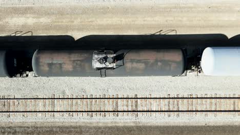 Vista-De-Pájaro-Dolly-Right-Drone-Shot-Volando-Sobre-La-Estación-De-Ferrocarril-En-Un-Ambiente-Desértico-En-Un-Día-Soleado-Sobre-Trenes-Tanque-Negros