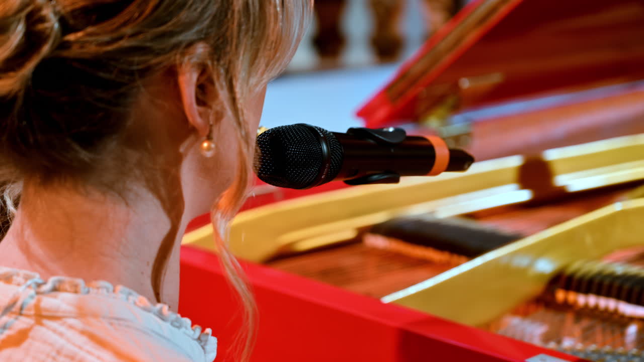 Vrouw die in de microfoon zingt en op een rode piano speelt