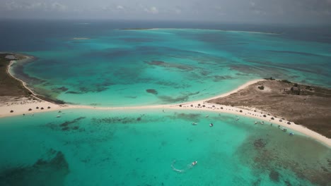 Ein-Atemberaubendes-Türkisfarbenes-Meer-Und-Ein-Sandstrand-Mit-Verstreuten-Booten-Auf-Cayo-De-Agua,-Luftaufnahme