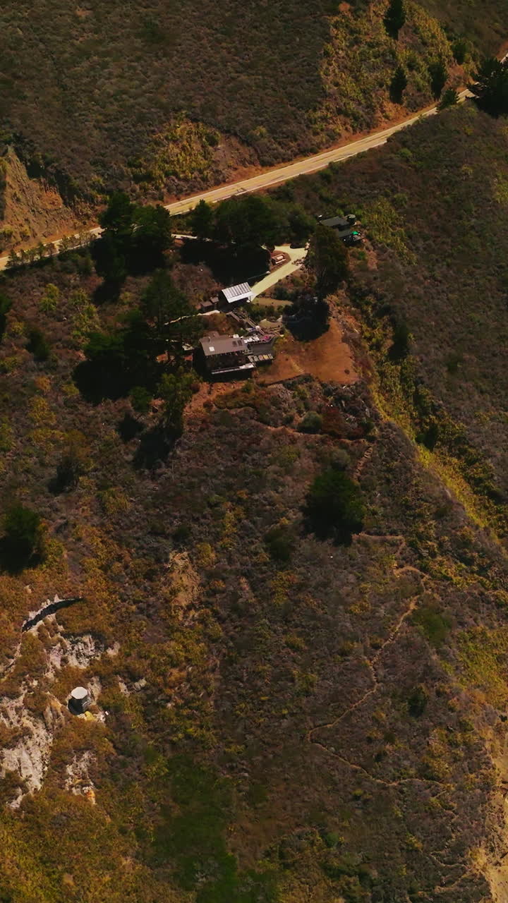 View of the houses build on the sloping mountains of the pacific coastline in California, USA. Motorway built in the mountains along the shore. Vertical video