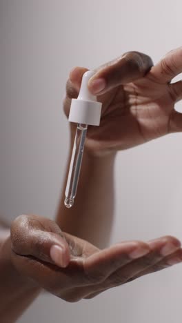 close up of woman squeezing dropper from bottle of beauty product on white background 5