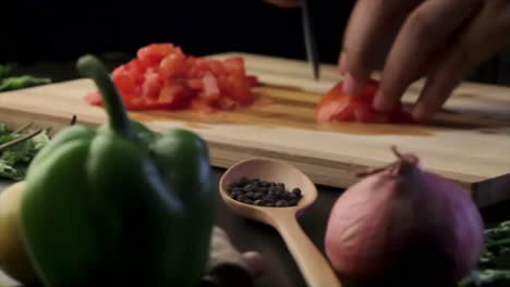 chopping tomato on a wooden chopping board with a sharp knife in the kitchen, cutting vegetables