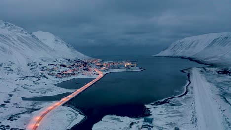 aerial backwards shot of lighting bridge and magical siglufjordur city in north iceland during mystic clouds at sky - beautiful snowy evening in winter