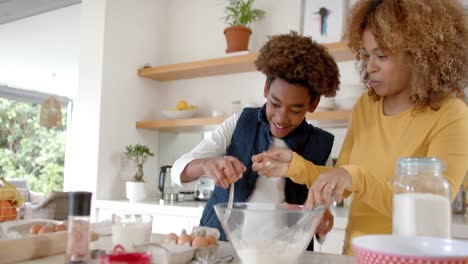 happy african american mother and son baking in kitchen, slow motion
