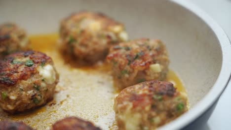 unrecognizable person cooking meatballs on frying pan with oil