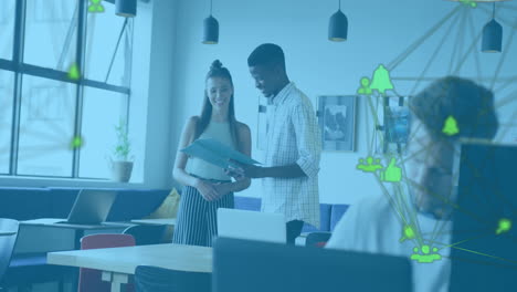 Animation-of-two-globes-of-digital-icons-spinning-against-diverse-man-and-woman-discussing-at-office