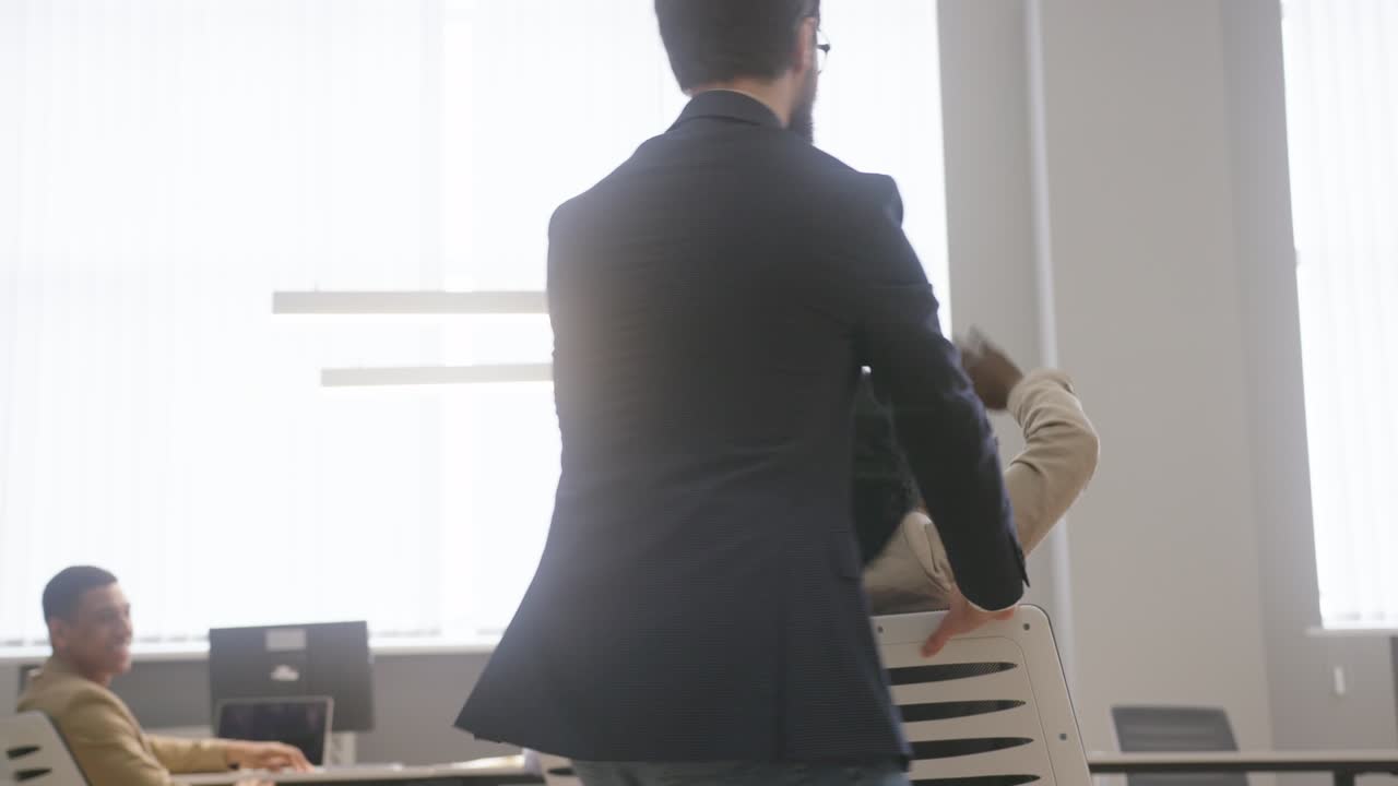 남자가 사무실 의자에 앉아 있는 아프리카계 미국인 여자를 회전시니다.