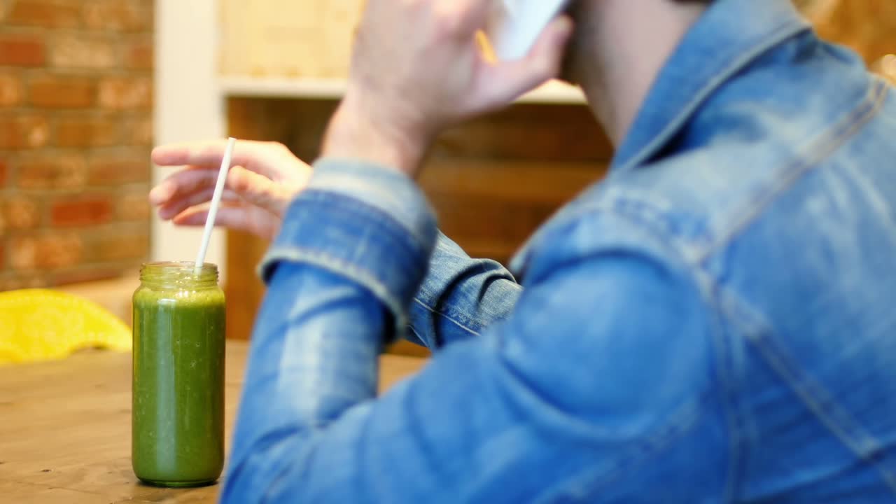 hombre hablando por teléfono móvil mientras bebe jugo