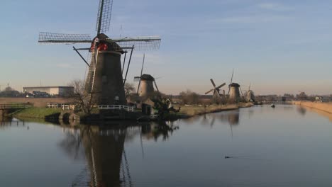 a boat moves along a canal in holland with windmills nearby