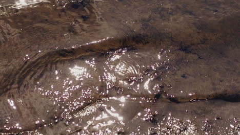 clear river waves roll on clayey bank at bright sunlight