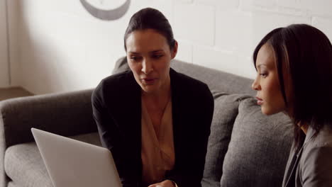 serious businesswomen discussing while looking on laptop