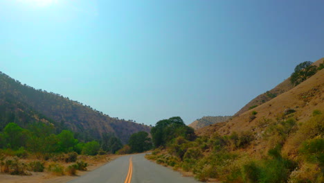 driving through mountains in southern california's mojave desert on a hot, bright day - driver point of view