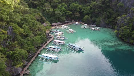 turistas en el paseo marítimo en el muelle de barcos turísticos del lago kayangan en la isla de coron