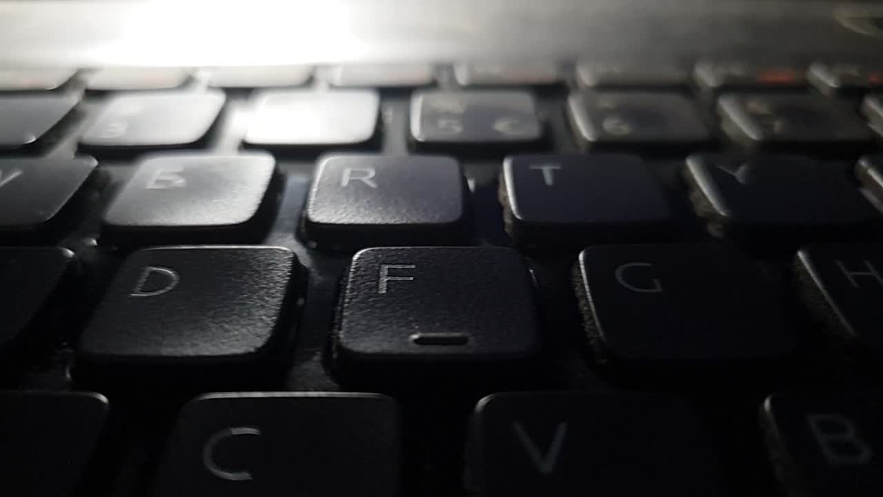 Dirty broken laptop keyboard with grime and dust sliding right over keys in slow motion footage