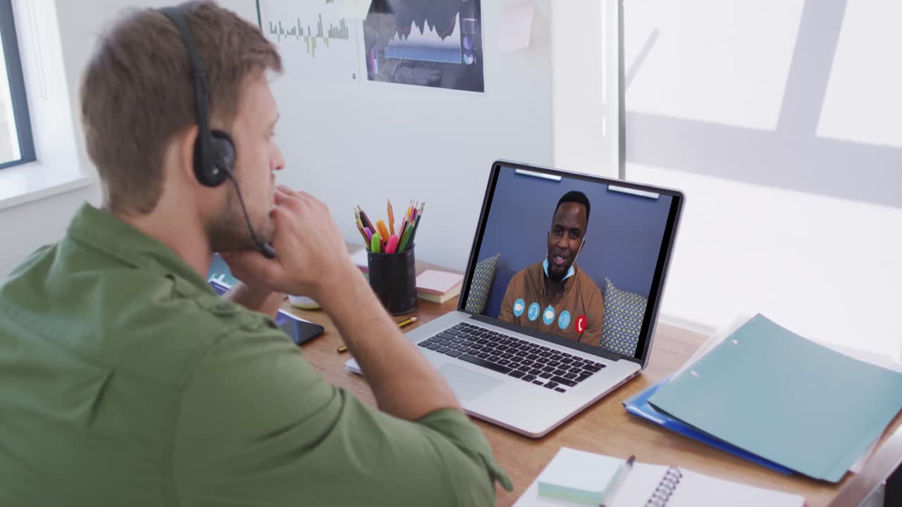 Caucasian man using laptop and phone headset on video call with male colleague