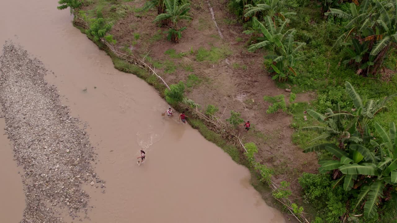 Crianças brincando à beira do rio em meio aos campos de arroz em Lamboya, Sumba