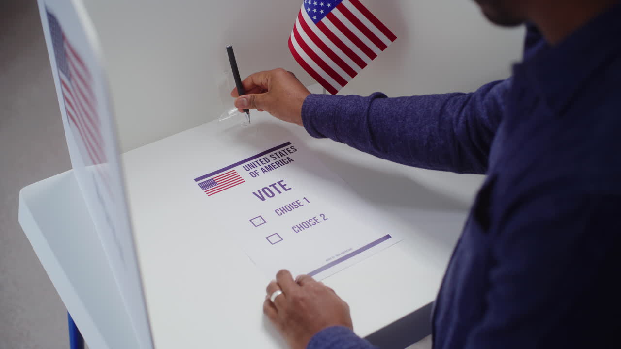 African American Male Voter Comes to Voting Booth and Fills out Paper Ballot African American Male Voter Comes to Voting Booth at Polling Station Makes Choice and Fills out Paper Ballot us Citizen during National Elections Day in the United States of America Civic Duty