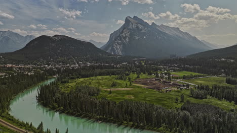 banff ab canada aerial v47 pintoresco paisaje de río bow alimentado por glaciares, establos en prados, pintoresca ciudad al pie de la colina, valle boscosa y cadenas montañosas de rundle - filmado con mavic 3 pro cine - julio 2023