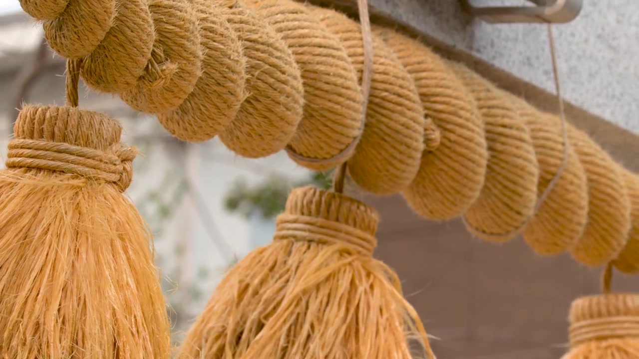 Una toma detallada en primer plano de una cuerda tradicional de paja shimenawa colgando en un santuario japonés