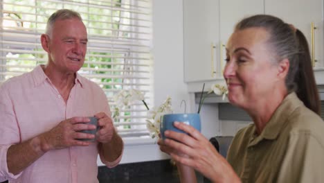 Caucasian-senior-couple-drinking-coffee-together-in-the-kitchen-at-home