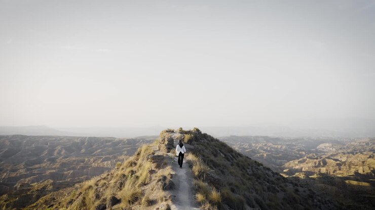 Donna che fa escursionismo da sola su un sentiero panoramico in cresta su una montagna nel deserto