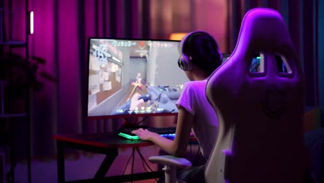 una adolescente asiática emocionada celebra la victoria y baila mientras juega videojuegos en la computadora, videojuegos de disparos en línea
